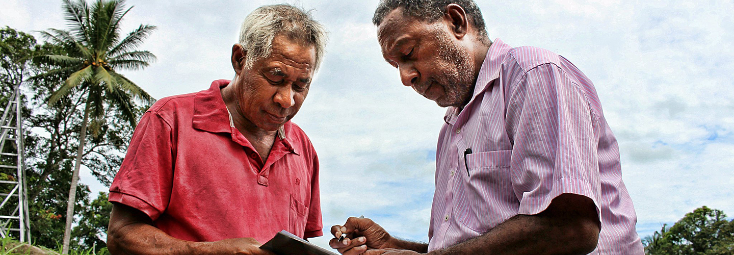 Works Coordinator and Vice Chairman of Rigo District Disaster Committee, Kone Burana, looks over Disaster Risk Reduction plans with Ward Councillor, Vanagi Kila.