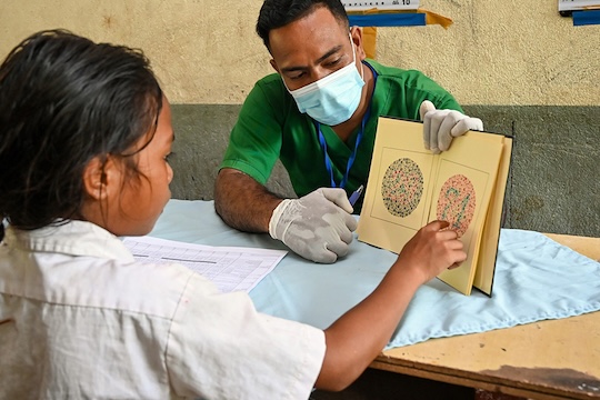 A healthcare worker in Timor-Leste conducts a vision screening for a young girl. The country is working to strengthen health services and build resilience to climate-related health risks in vulnerable communities.